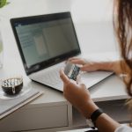Woman holding a payment card while working on a laptop