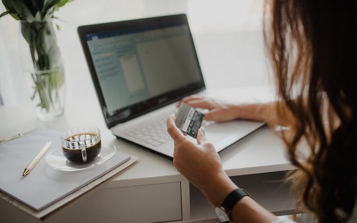Woman holding a payment card while working on a laptop