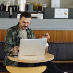 Man working on cloud apps on a laptop in a cafe