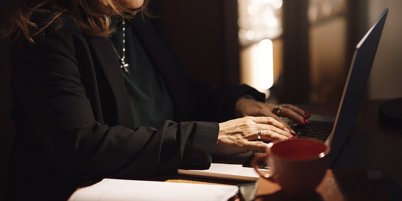 Businesswoman reading email on a laptop in a dim office