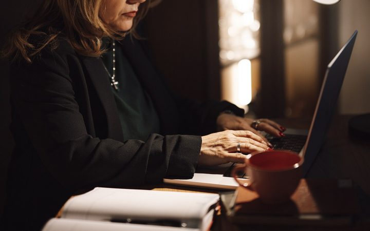 Businesswoman reading email on a laptop in a dim office