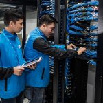 Engineers inspecting network equipment in a server room