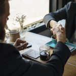 Two business partners shaking hands over a table