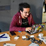 A hacker typing on a sticker-covered Linux laptop