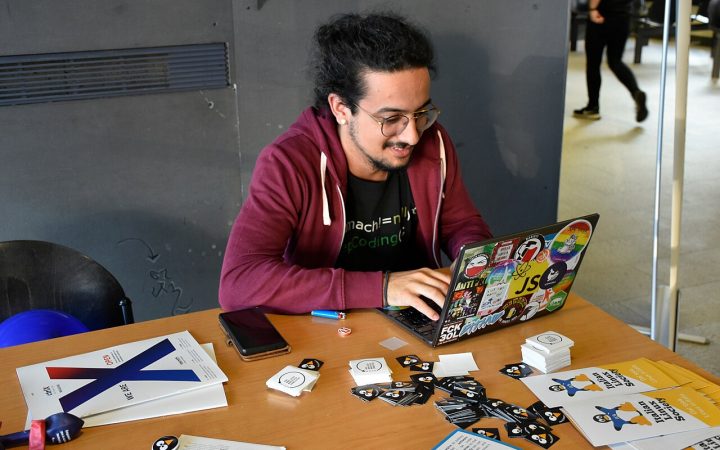 A hacker typing on a sticker-covered Linux laptop